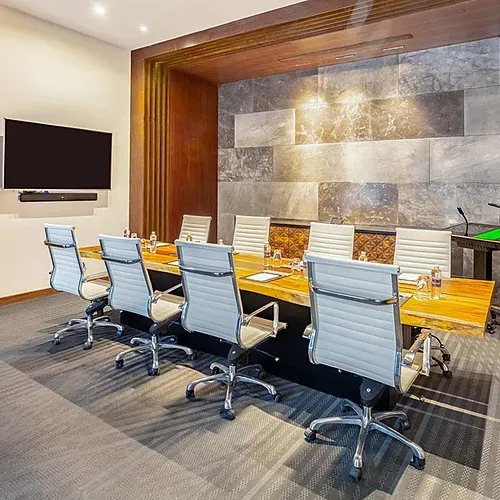 Modern boardroom at The Fives Corpo, featuring a wooden table and white chairs.