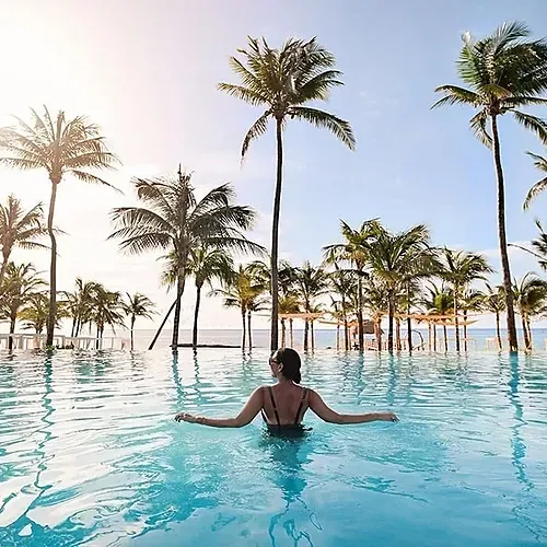 Relax in The Fives Corpo's infinity pool, surrounded by palm trees and ocean views.