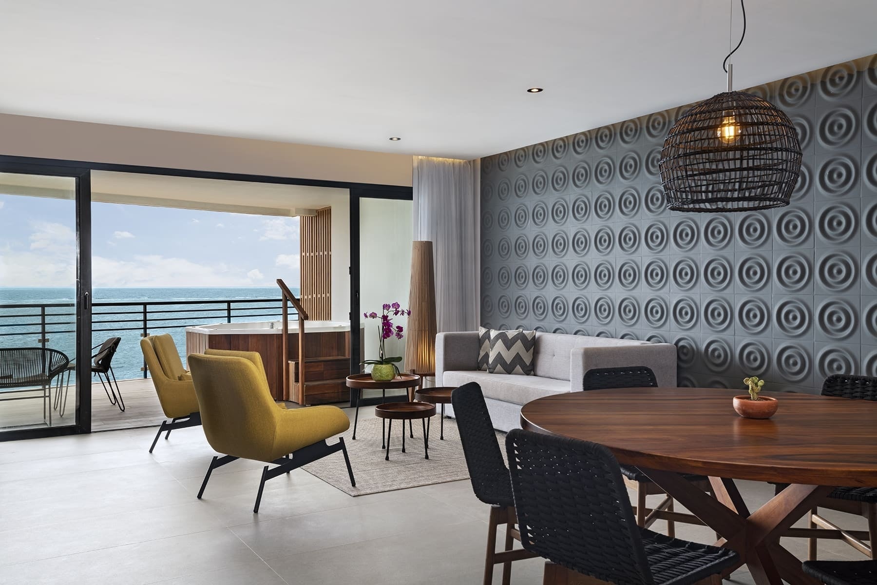 Modern hotel suite with ocean view, private balcony, hot tub, living room, and dining area.