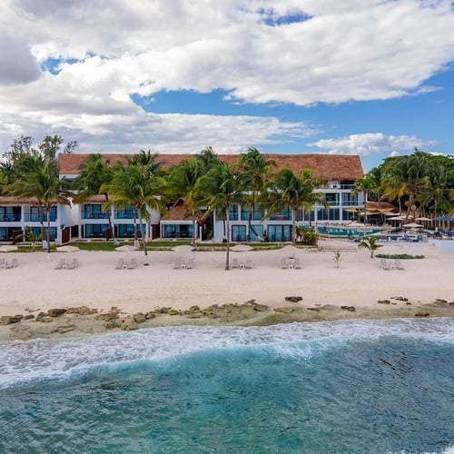 an aerial view of a beach resort with a large building in the background