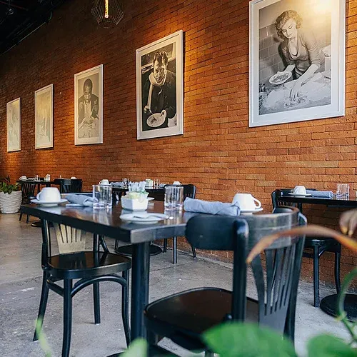 The Fives Corpo: Industrial chic restaurant with iconic art and set tables.