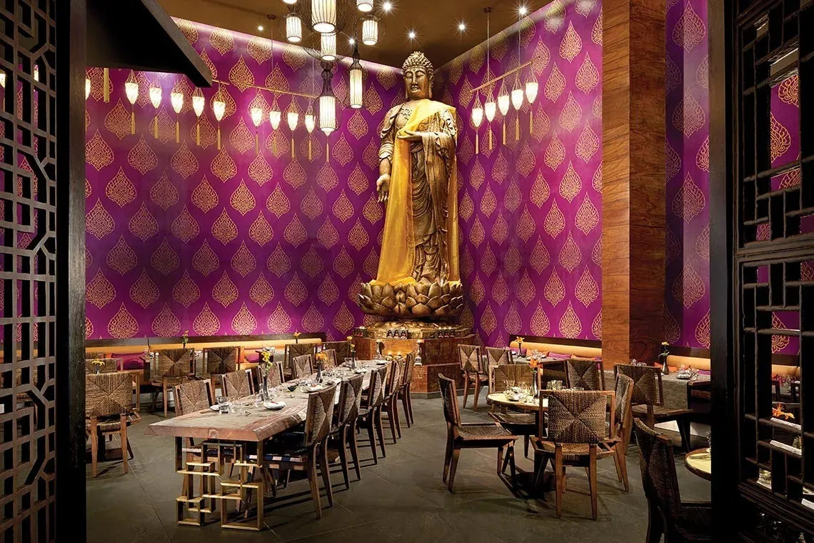El hotel The Fives Corpo ofrece un restaurante con decoración asiática, un buda dorado y mesas elegantes.