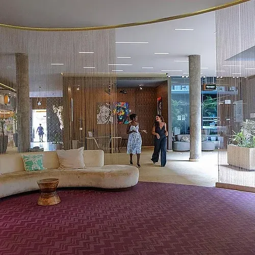 The Fives Corpo: Modern lobby featuring a curved sofa and vibrant art.