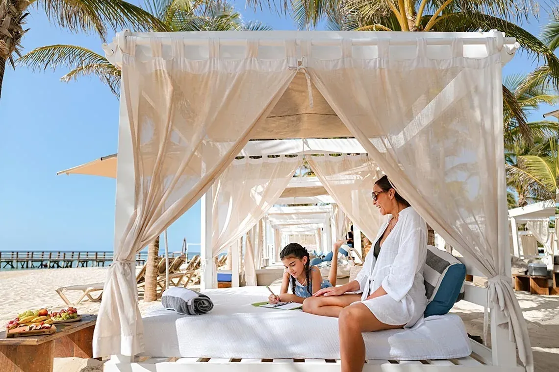 Madre e hija relajándose en cabaña en The Fives Beach Hotel, México.