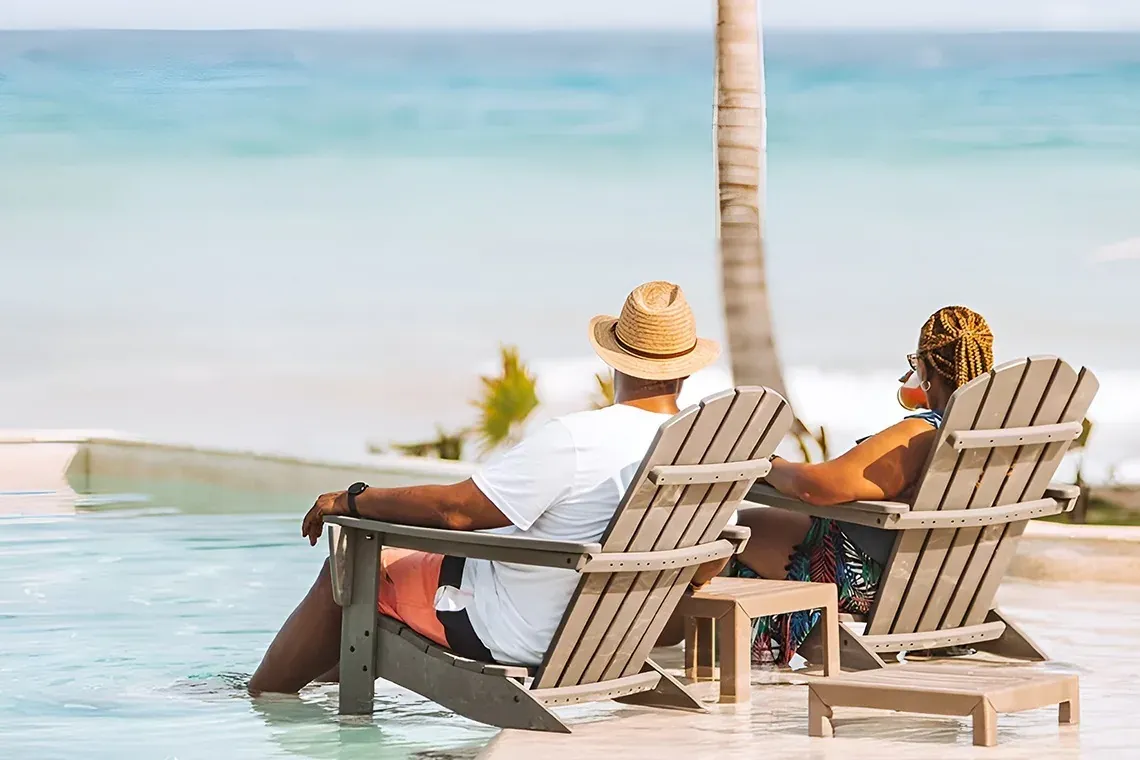 Couple relaxing at The Fives Corpo, beach chairs overlooking turquoise ocean.