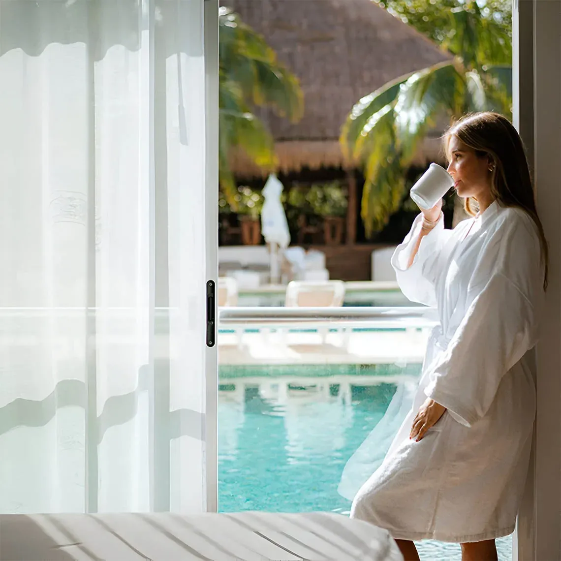 Woman in robe enjoying coffee by the pool at The Fives Corpo.