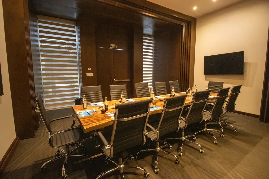 Modern boardroom at The Fives Corpo featuring a wood table and executive chairs.