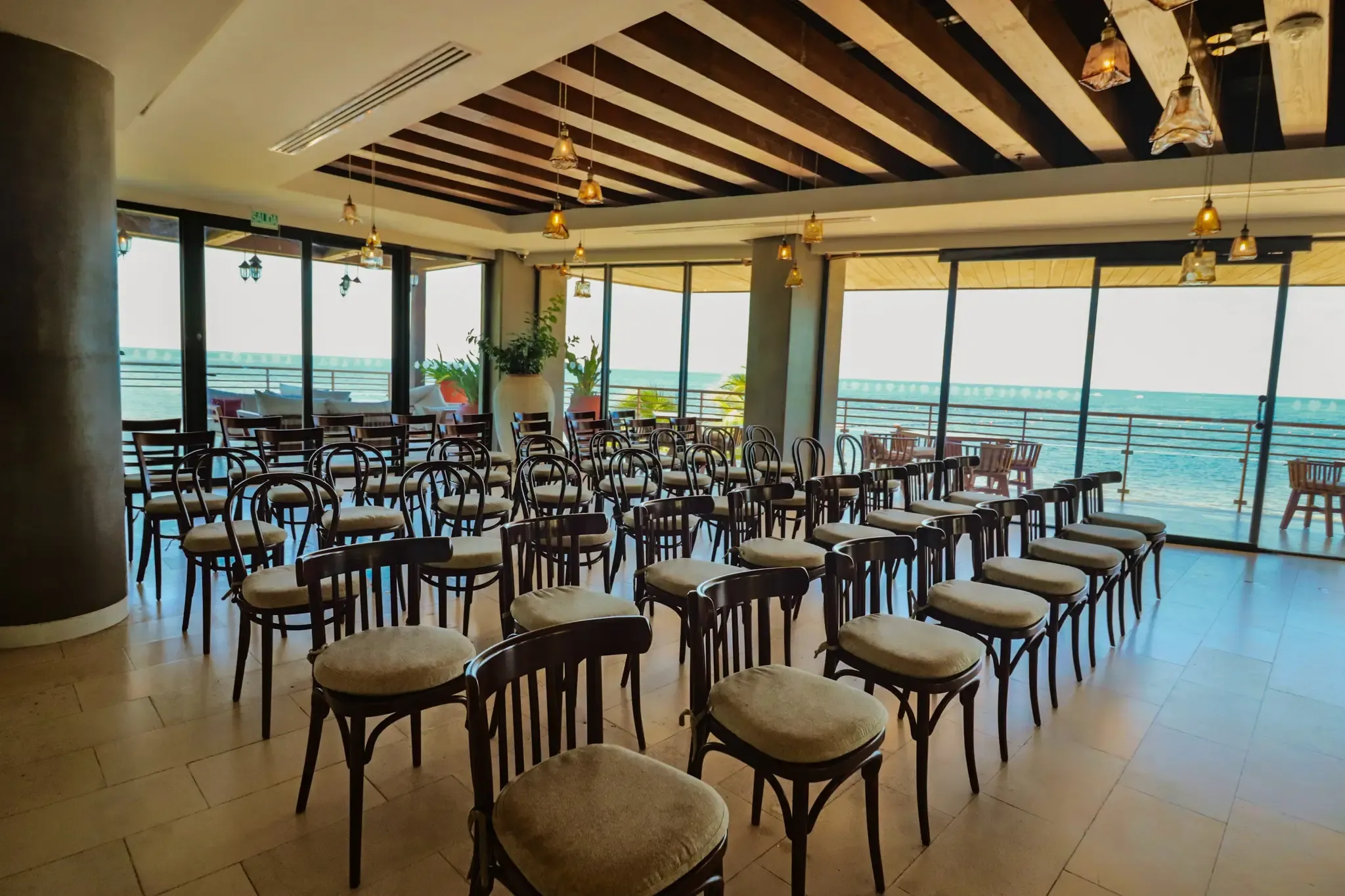 Sillas en un salón de eventos con vista al mar, perfecto para conferencias o bodas. The Fives Corpo
