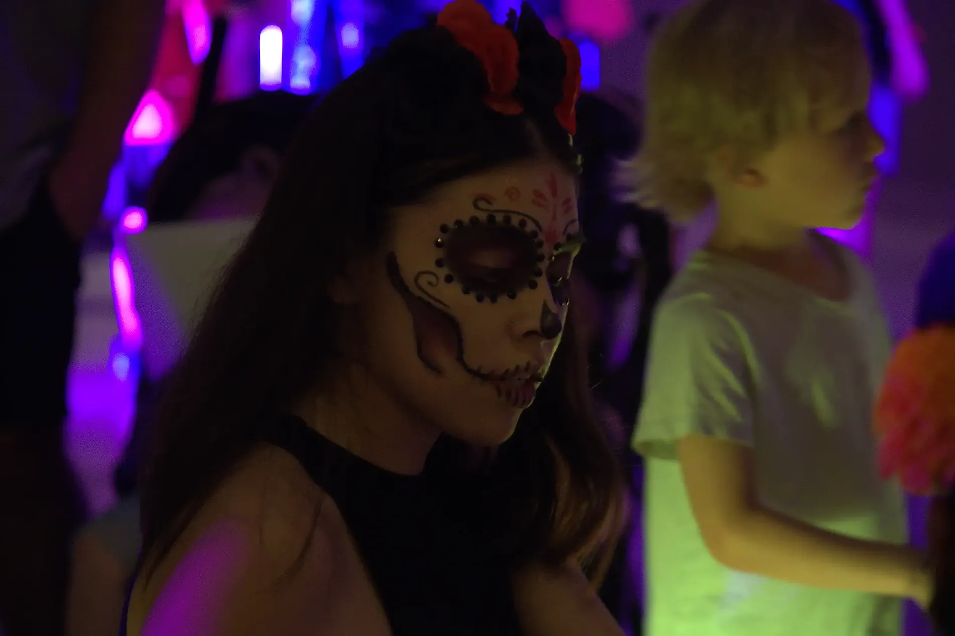 Niña con maquillaje de calavera mexicana, luces de fiesta, ideal para Ofertas de Verano en Riviera Maya | The Fives Hotels.