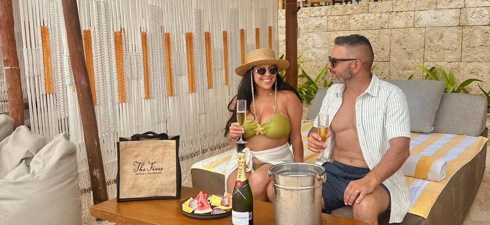 Febrero en The Fives: amor, eventos y Riviera Maya. Pareja celebra con champagne en resort de lujo.