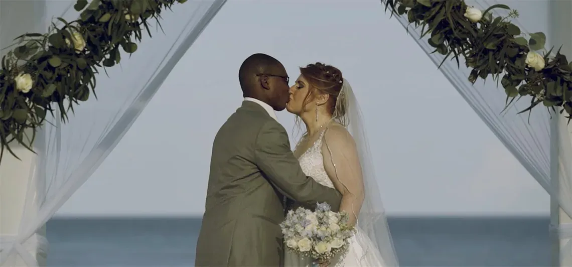 Newlyweds kiss under a decorated wedding arch at The Fives Corpo.