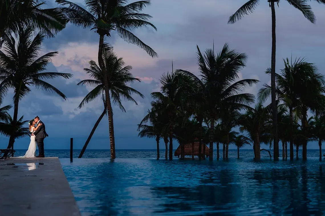 Couple in love at The Fives Corpo, by infinity pool and palm trees at dusk.