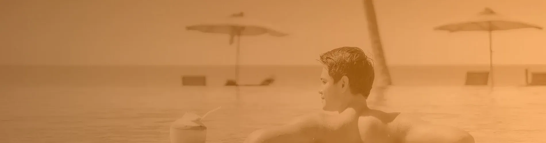 Man enjoying coconut drink in The Fives Corpo infinity pool.