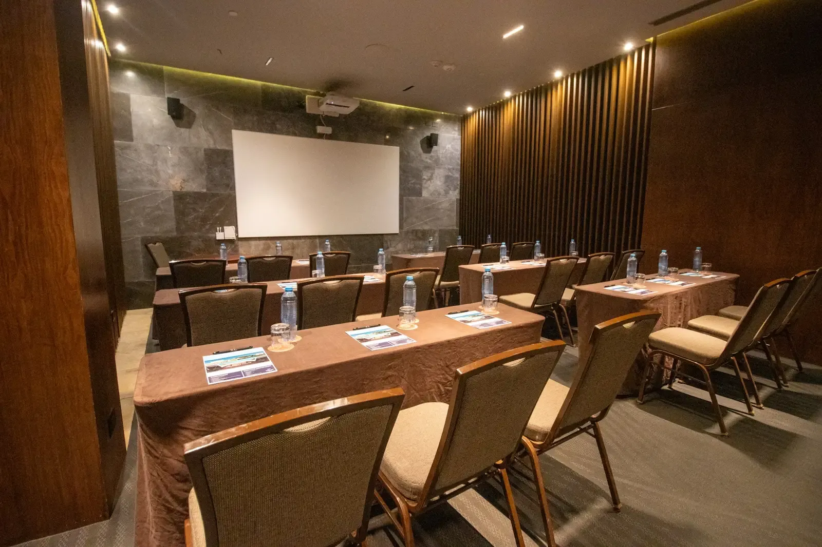 The Fives Corpo: Conference room setup with tables, chairs, and projector screen for business meetings.