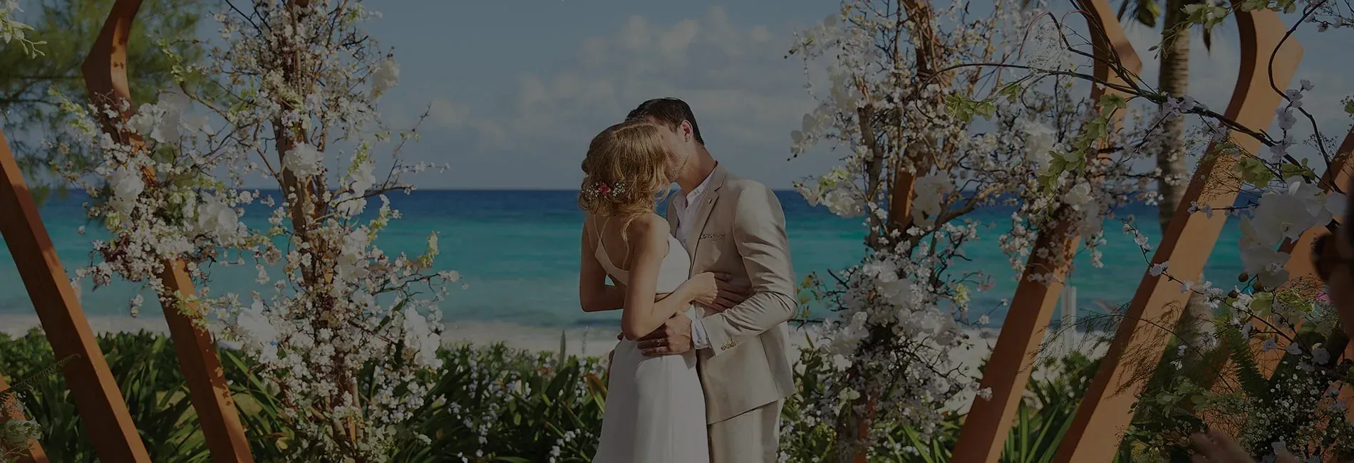 The Fives Corpo wedding: Couple kissing by the Caribbean Sea with floral decor.