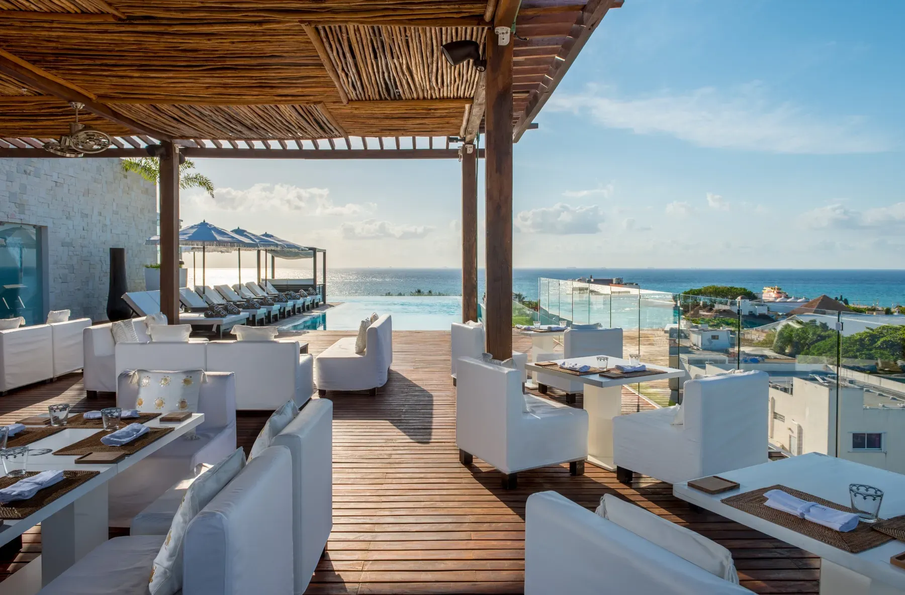 Luxury rooftop restaurant patio with infinity pool and ocean views, perfect for The Fives Corpo.