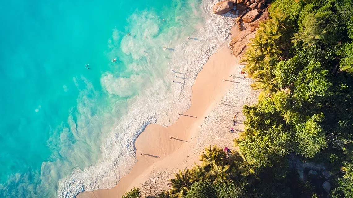Las Fives Corpo: Paraíso tropical con playa de arena, aguas turquesas y vegetación exuberante.