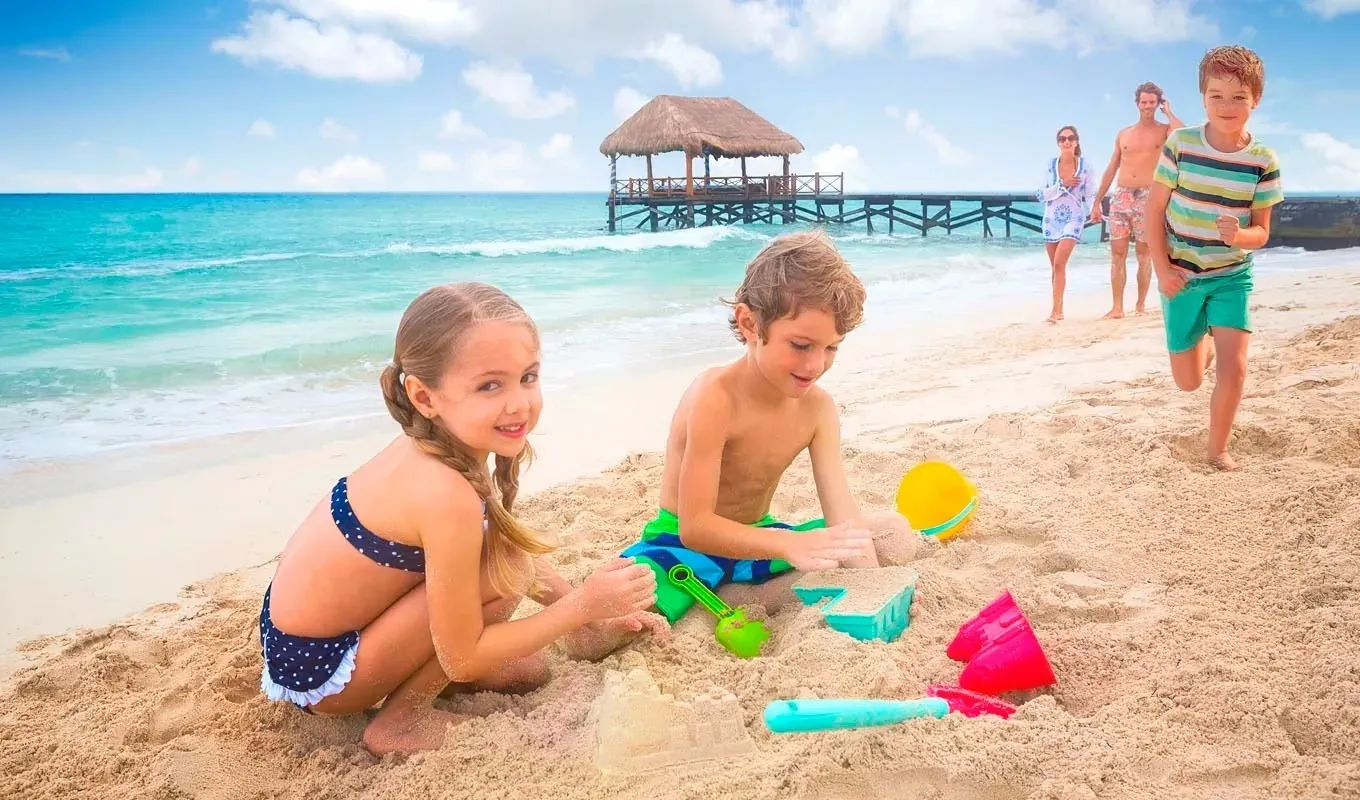 ¡Resort ideal para familias! Niños construyen castillos de arena, padres pasean en playa paradisíaca. Elegidos como el mejor resort para familias grandes.