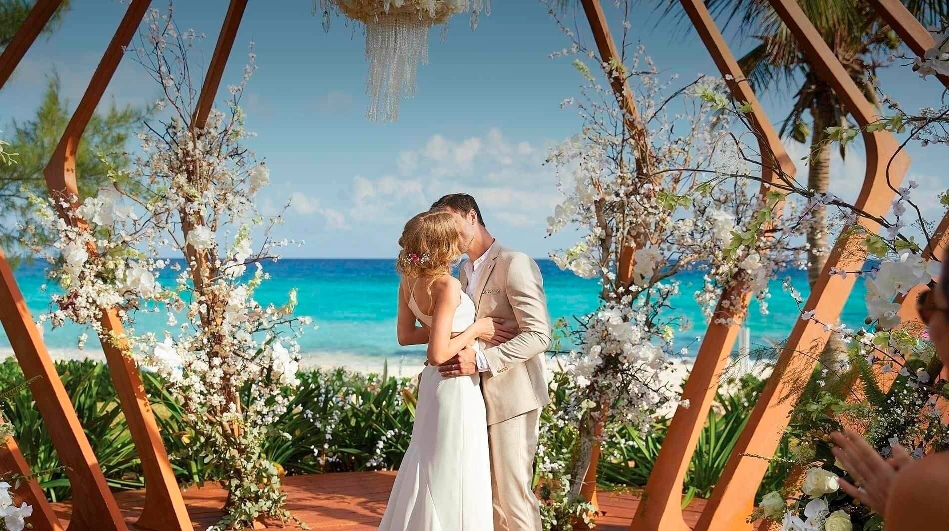 a bride and groom kiss under a wooden arch