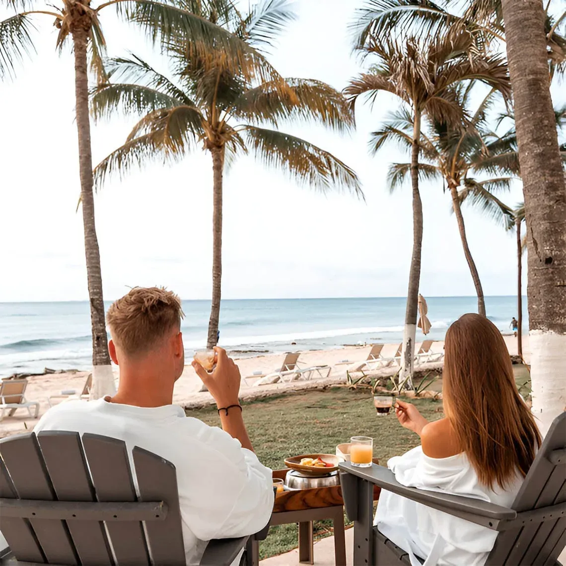The Fives Corpo: couple enjoying sunrise with ocean and palm trees view.