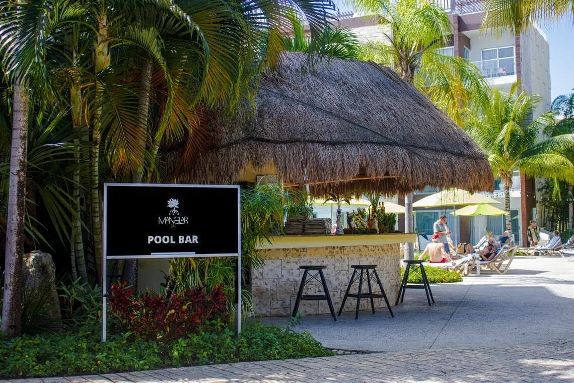 Pool bar de The Fives Corpo con palmeras y tumbonas.
