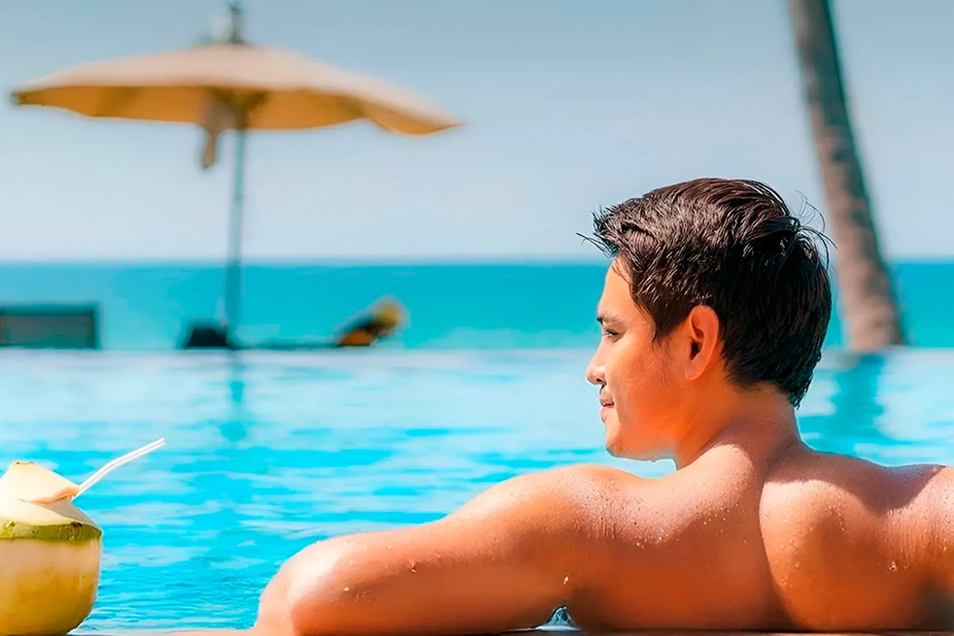 Hombre disfrutando de un coco en la piscina en The Fives Hotels.