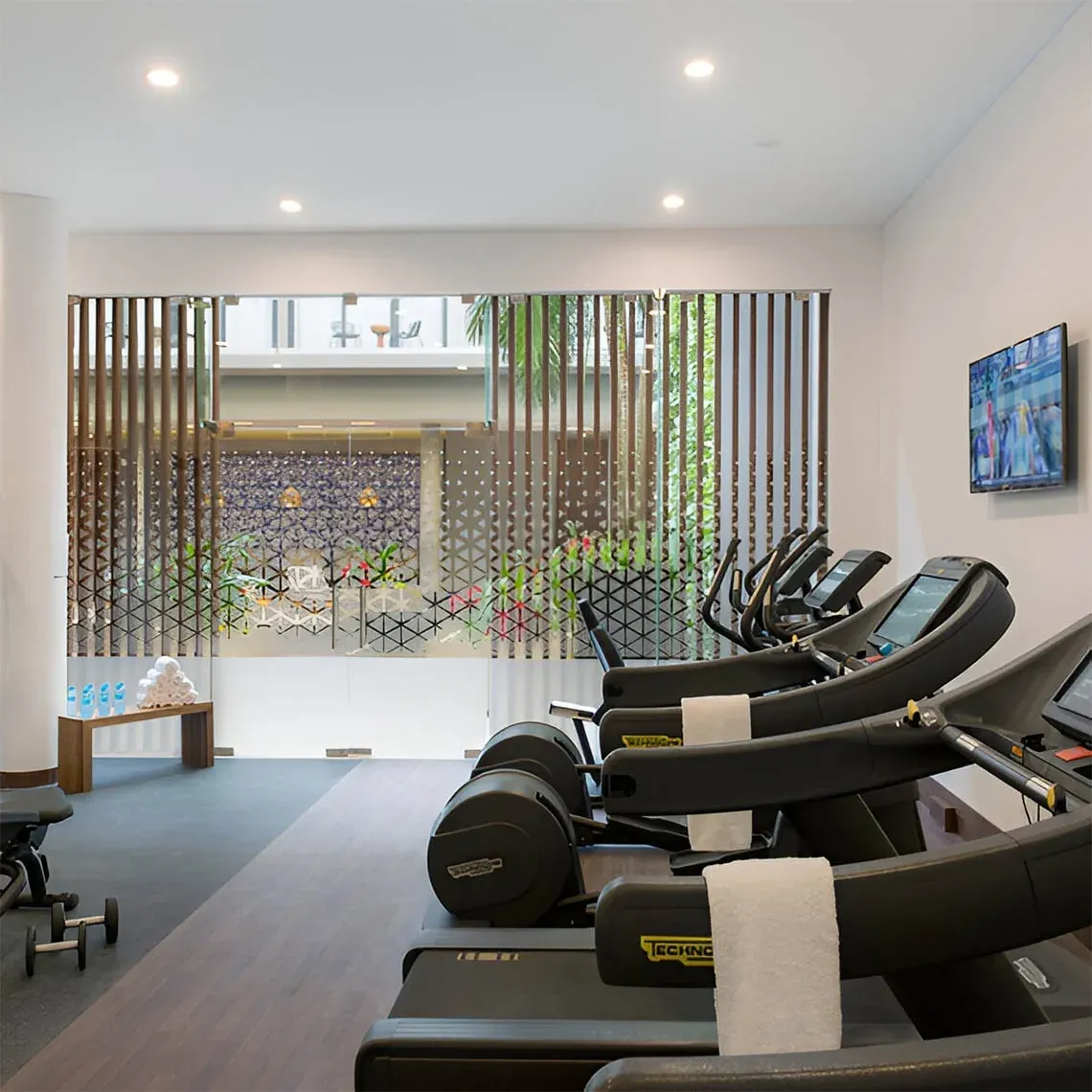 Moderno gimnasio en The Fives Corpo con cintas de correr y ventanas con diseño.