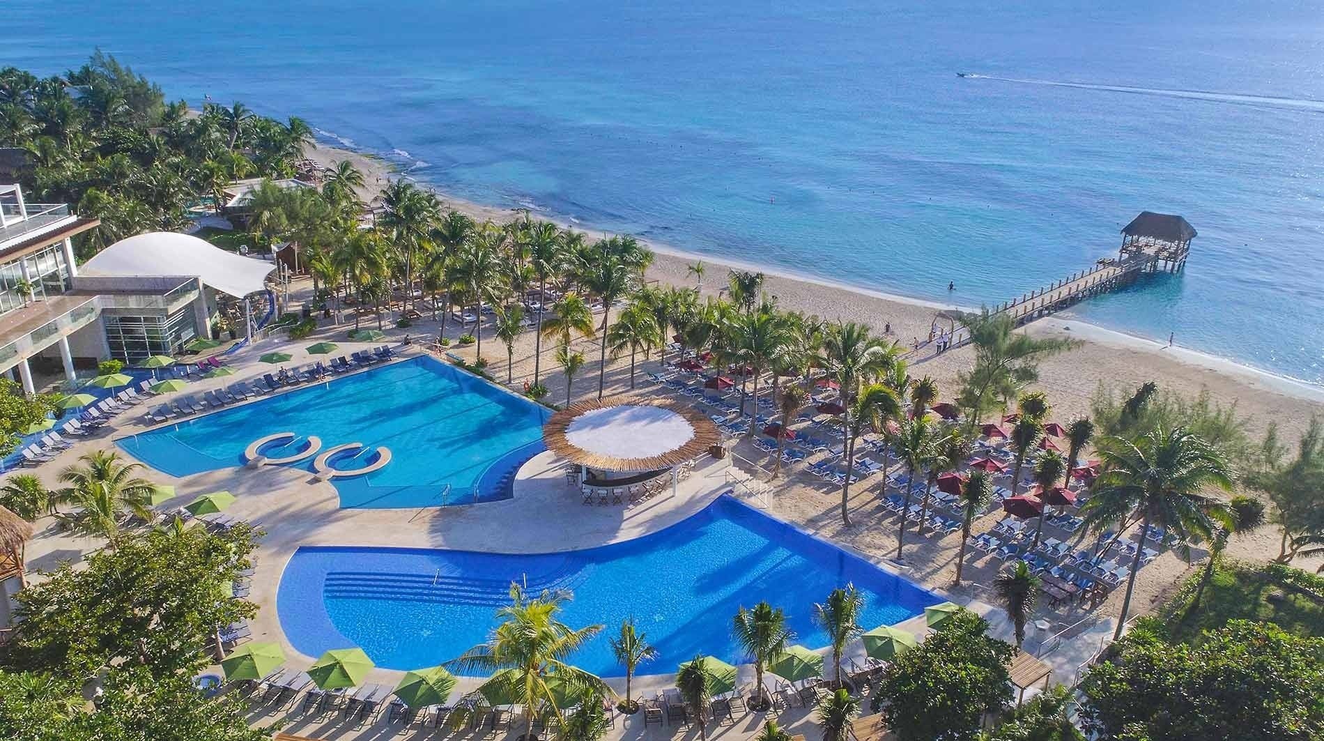 una vista aérea de una playa con piscinas y palmeras