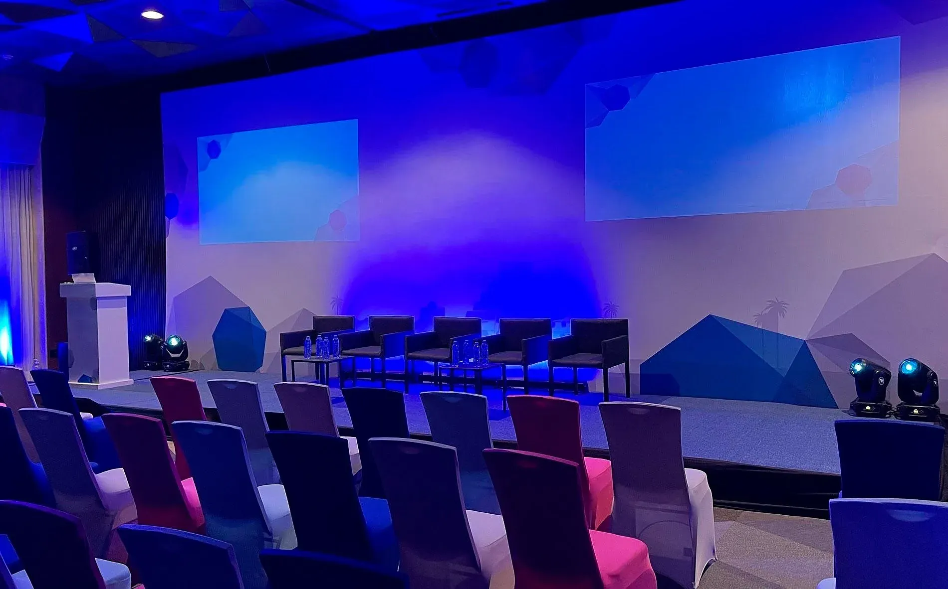 Modern event space with stage, seating, and screens for Meetings & Events at The Fives Hotels.