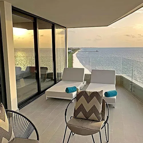 The Fives Corpo balcony with ocean view and chaises at sunset.