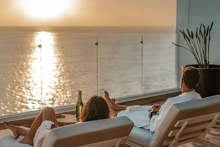 Couple relaxing at The Fives Corpo with sea view and champagne.