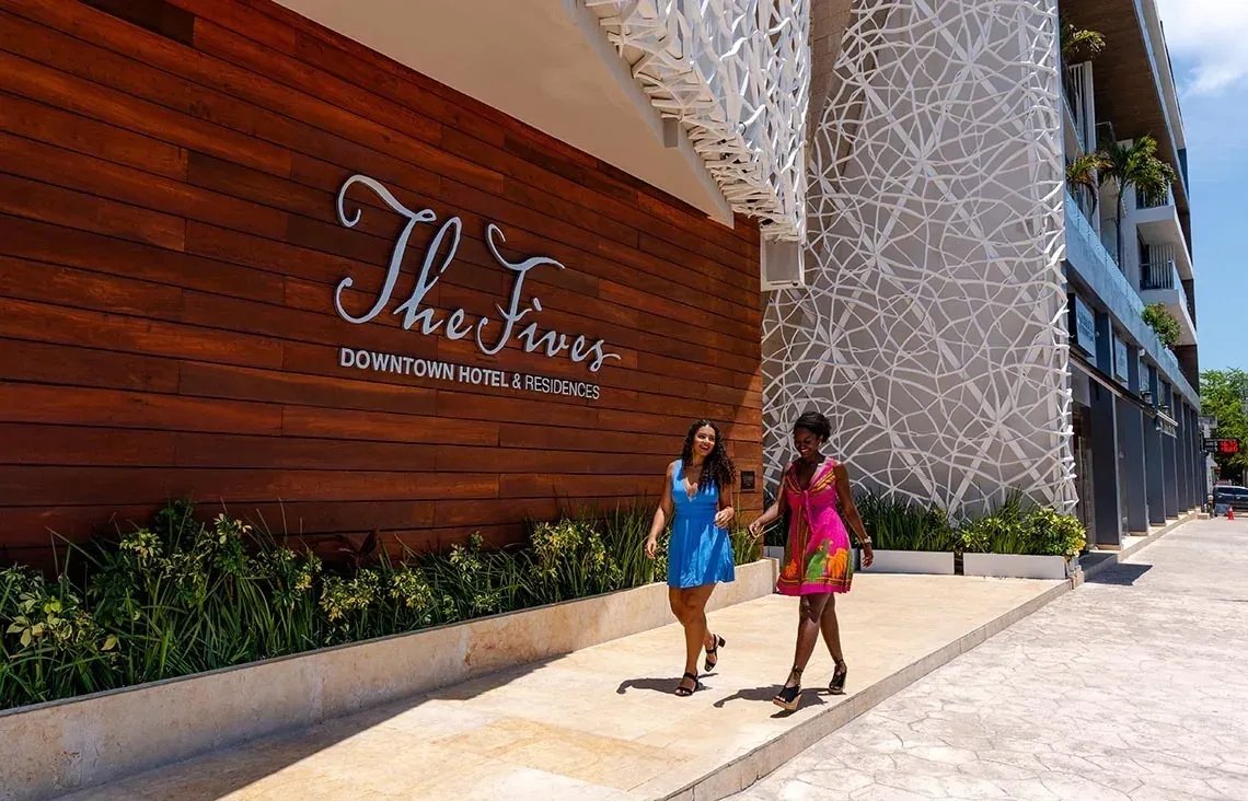 Two women walking by The Fives Downtown Hotel entrance. Visit The Fives Downtown Hotel - Curio Collection by Hilton official website.