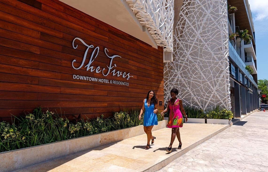 Two women walking by The Fives Downtown Hotel entrance. Visit The Fives Downtown Hotel - Curio Collection by Hilton official website.