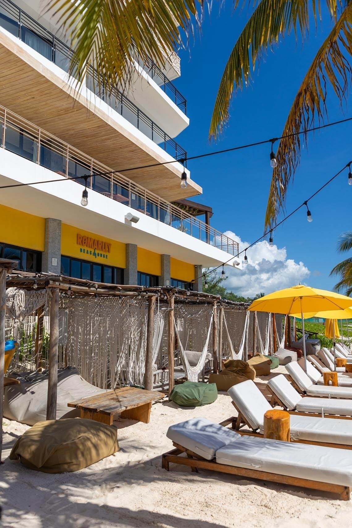 The Fives Oceanfront Riviera Maya: playa, hamacas y tumbonas bajo palmeras.