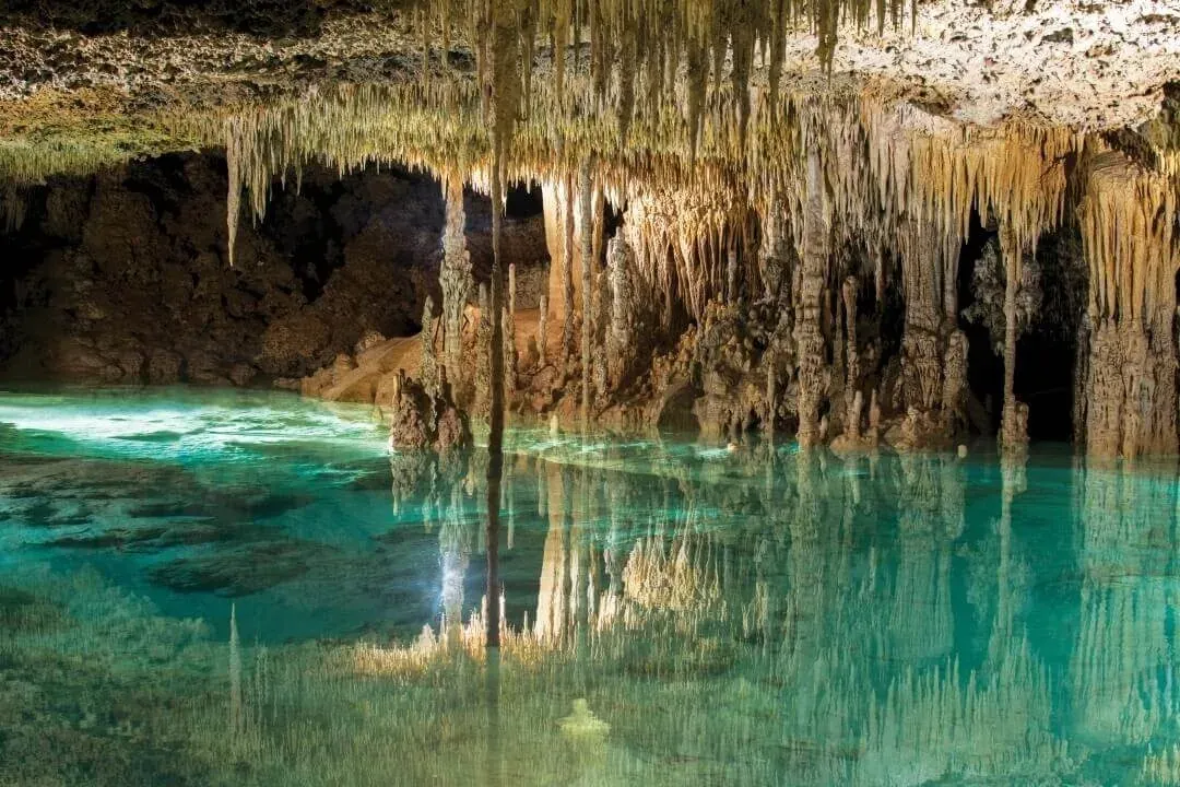 Cenote cristalino en The Fives Corpo: estalactitas, agua turquesa y reflejos.