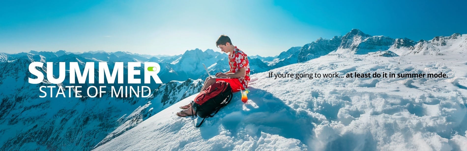 A man in a Hawaiian shirt and flip-flops works on a laptop on a snow-covered mountain with a cocktail, embodying a "summer state of mind" for work, despite the wintry setting.