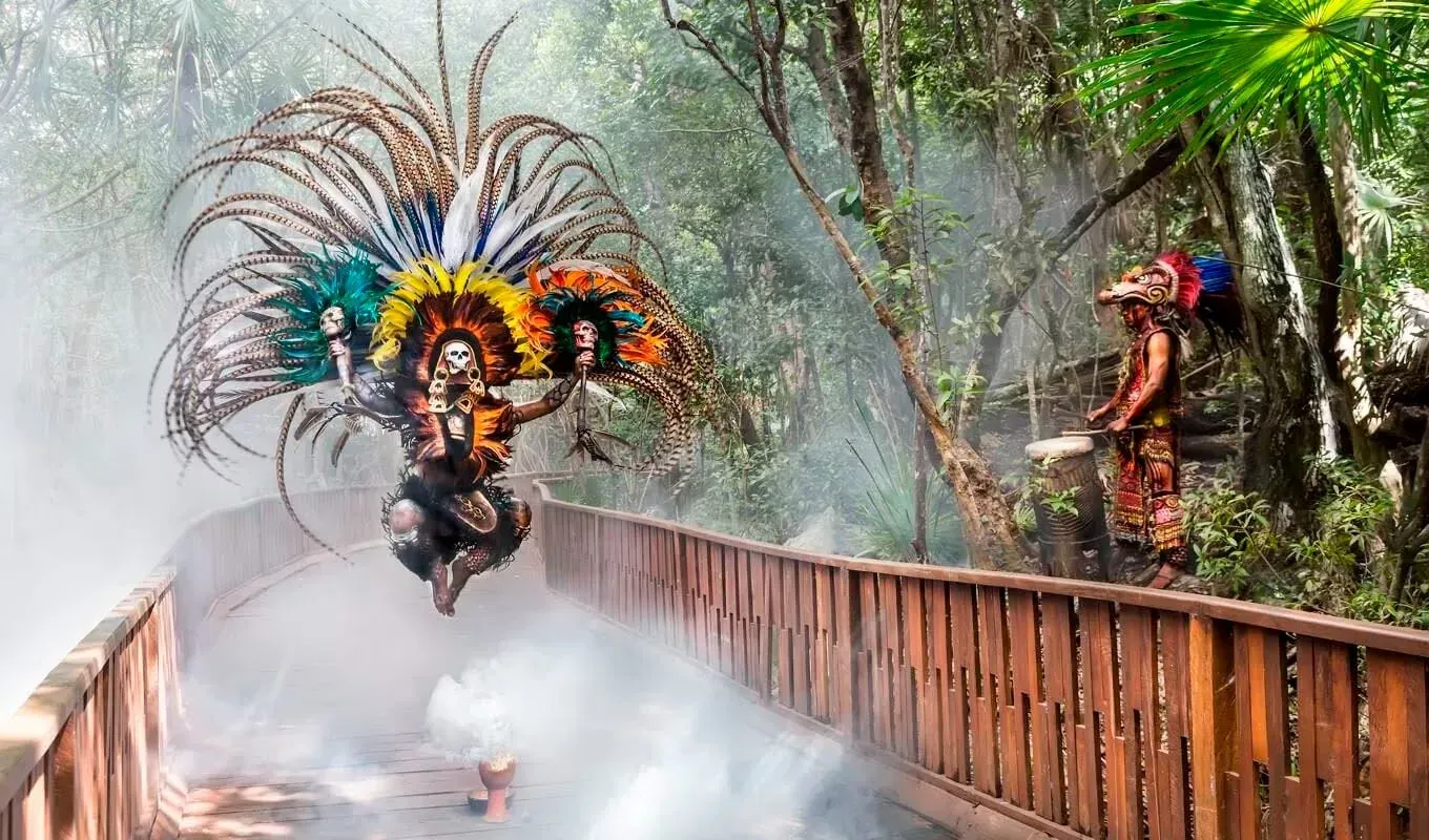 Descubre Riviera Maya: danza ritual y tamborista en pasarela boscosa. ¡Vive la magia con The Fives Hotels!