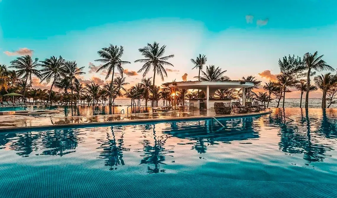 Piscina infinita con palmeras y bar al atardecer. Galardonados en los Travellers Choice | The Fives Hotels