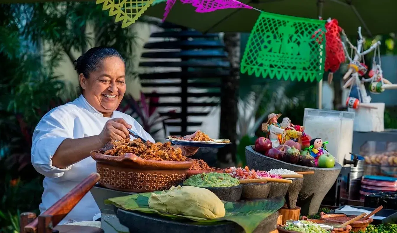 Chef sonriente sirve comida mexicana en Eventos Especiales de Septiembre en The Fives Hotels.