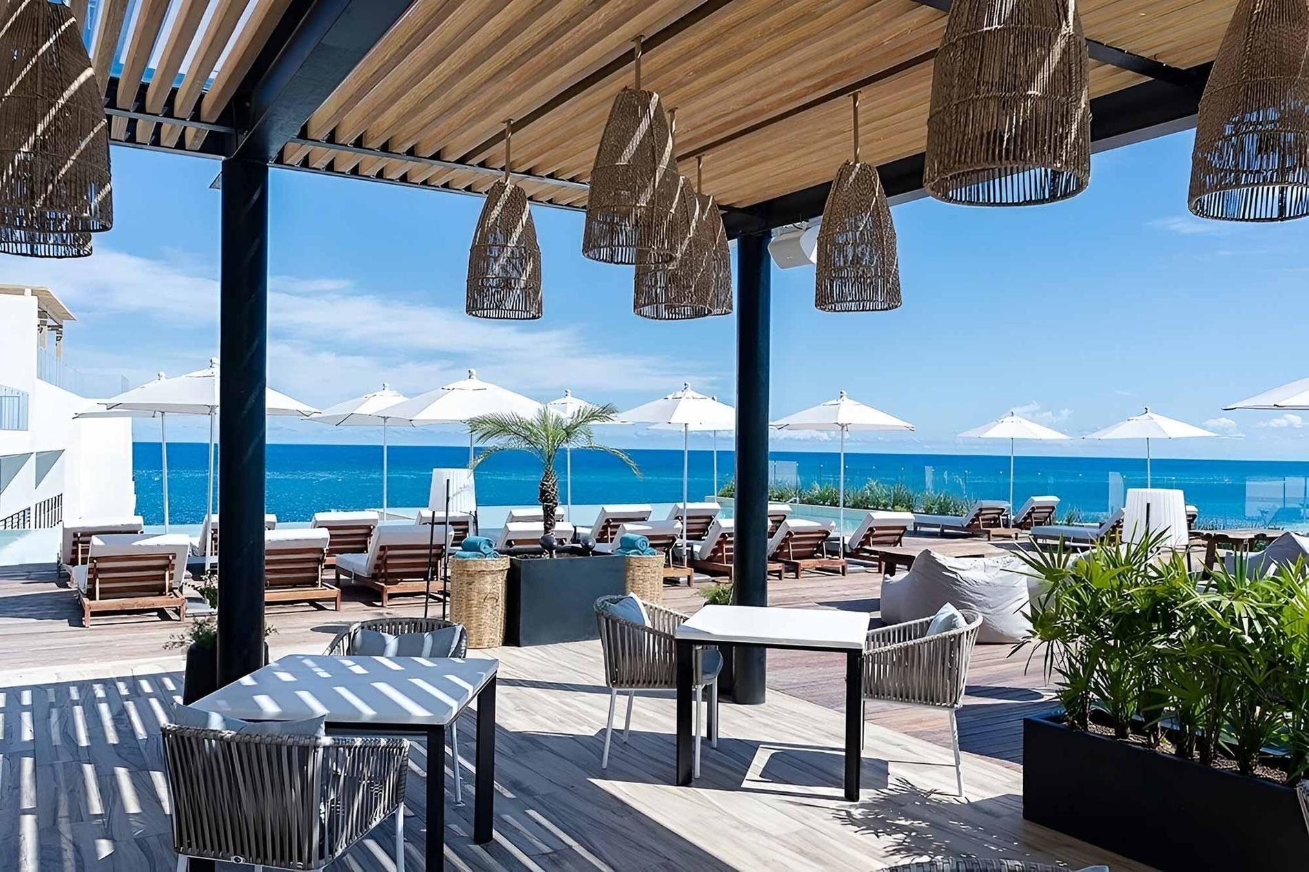 a patio with tables and chairs overlooking the ocean