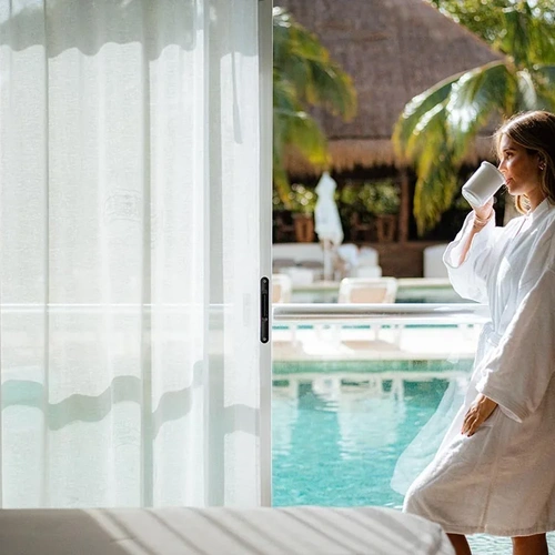 Woman enjoying coffee in robe by pool at The Fives Corpo.