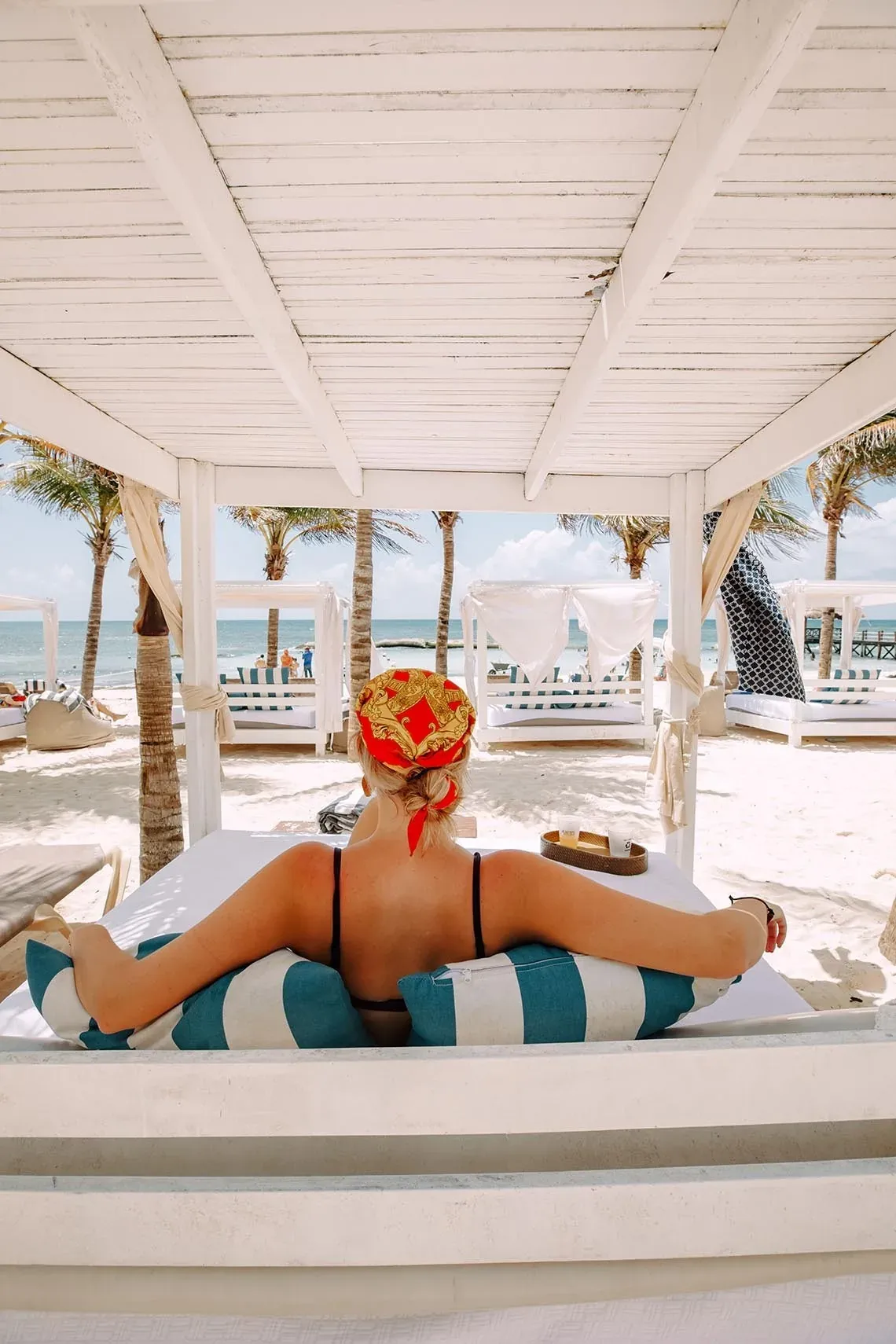 Mujer con pañuelo en la cabeza relajándose en The Fives Beach Hotel - Todo Incluido a la Carta | México | Web oficial.
