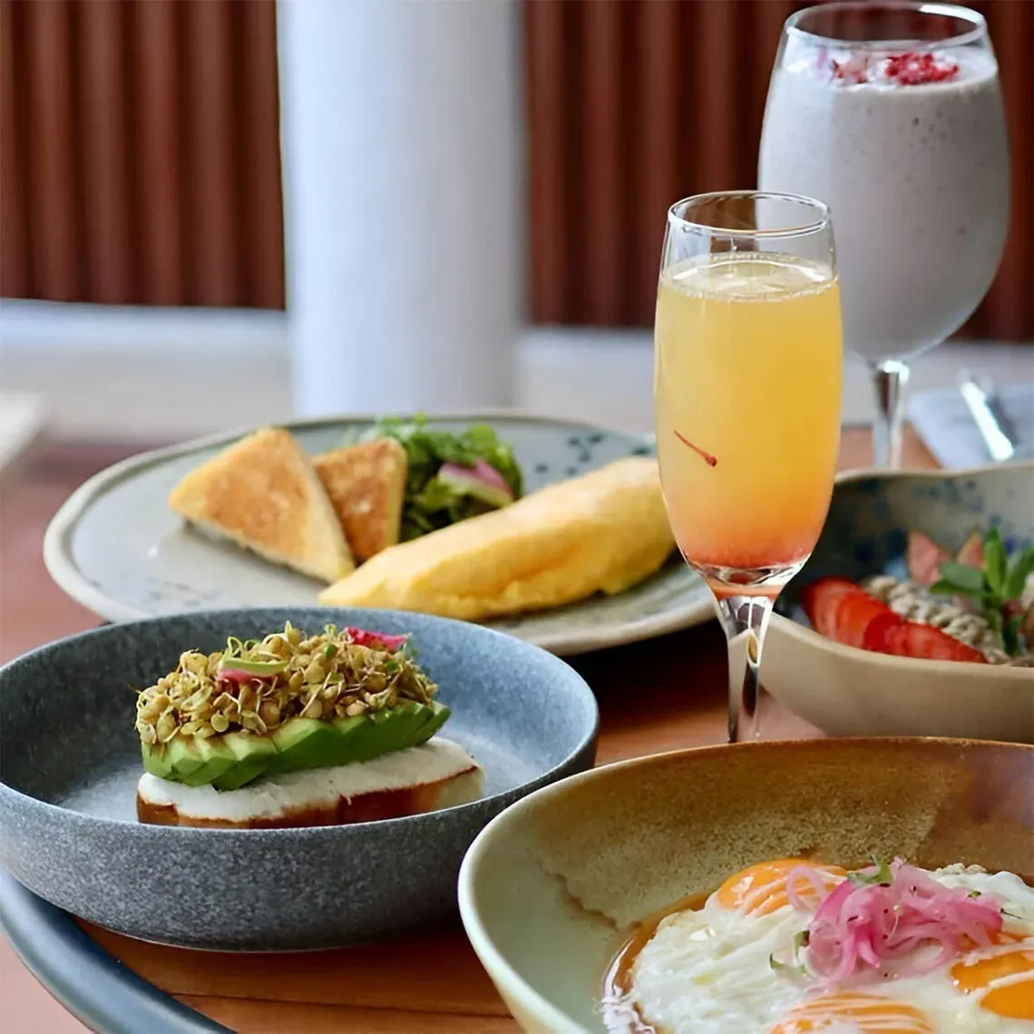 Gourmet breakfast at The Fives hotel: fried eggs, avocado toast, and mimosas.