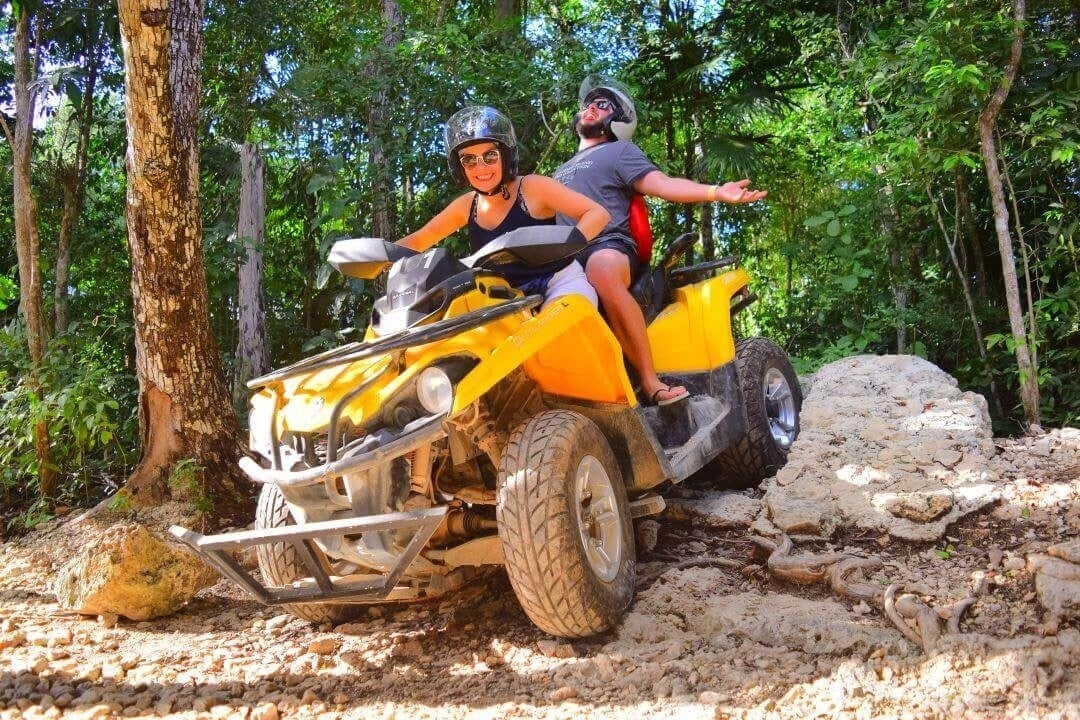 un grupo de personas están montando atvs por un camino fangoso .