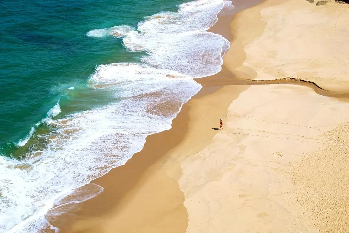Playa desierta con olas refrescantes; descubre la serenidad de The Fives Corpo.