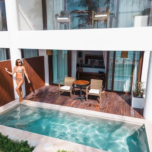a woman in a bikini is standing next to a swimming pool