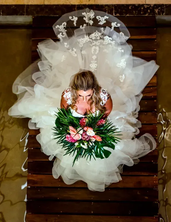 Bride in a flowing gown with a bouquet on a wooden dock, perfect for a wedding The Fives Corpo venue.