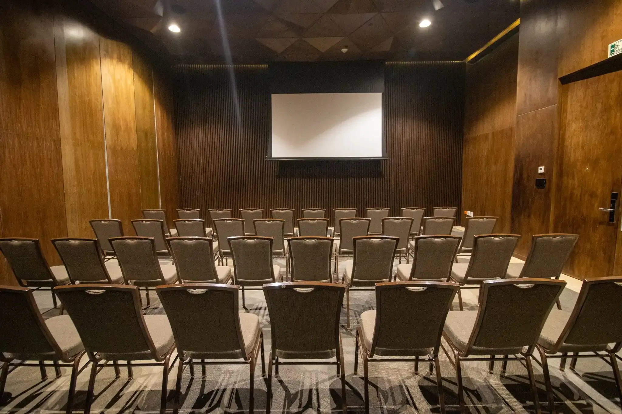 Theater-style seating in a hotel meeting room with a projector screen. The Fives Corpo