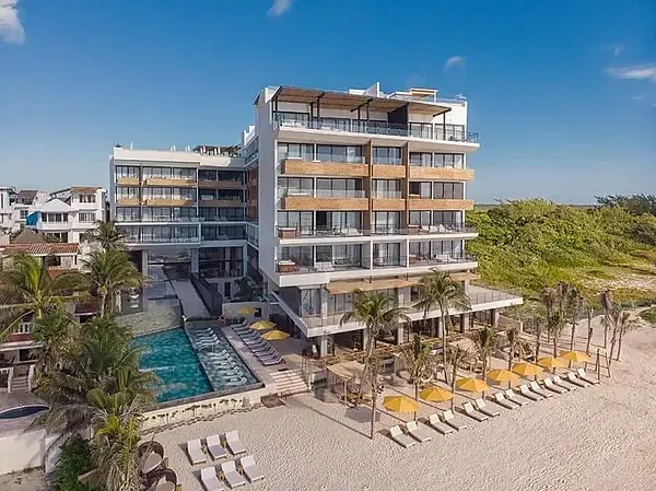 The Fives Corpo: Modern beachfront hotel with pool and loungers.