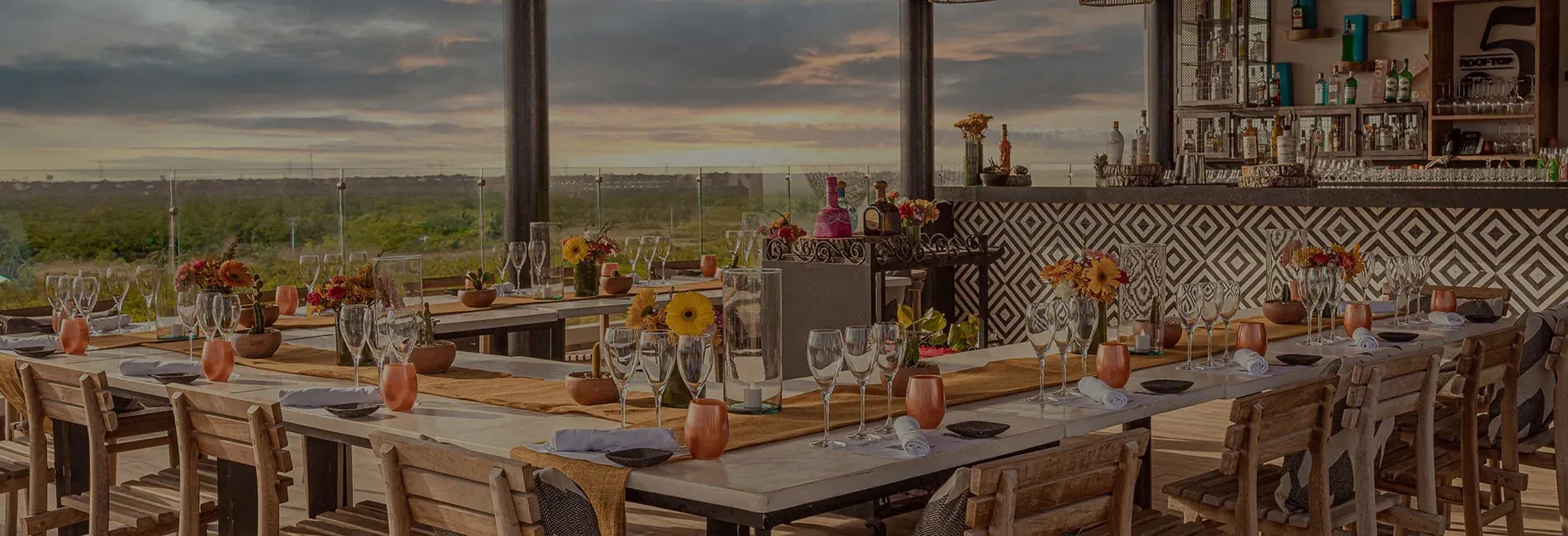 Outdoor dining at The Fives Corpo: sunset view, set tables, and floral arrangements.